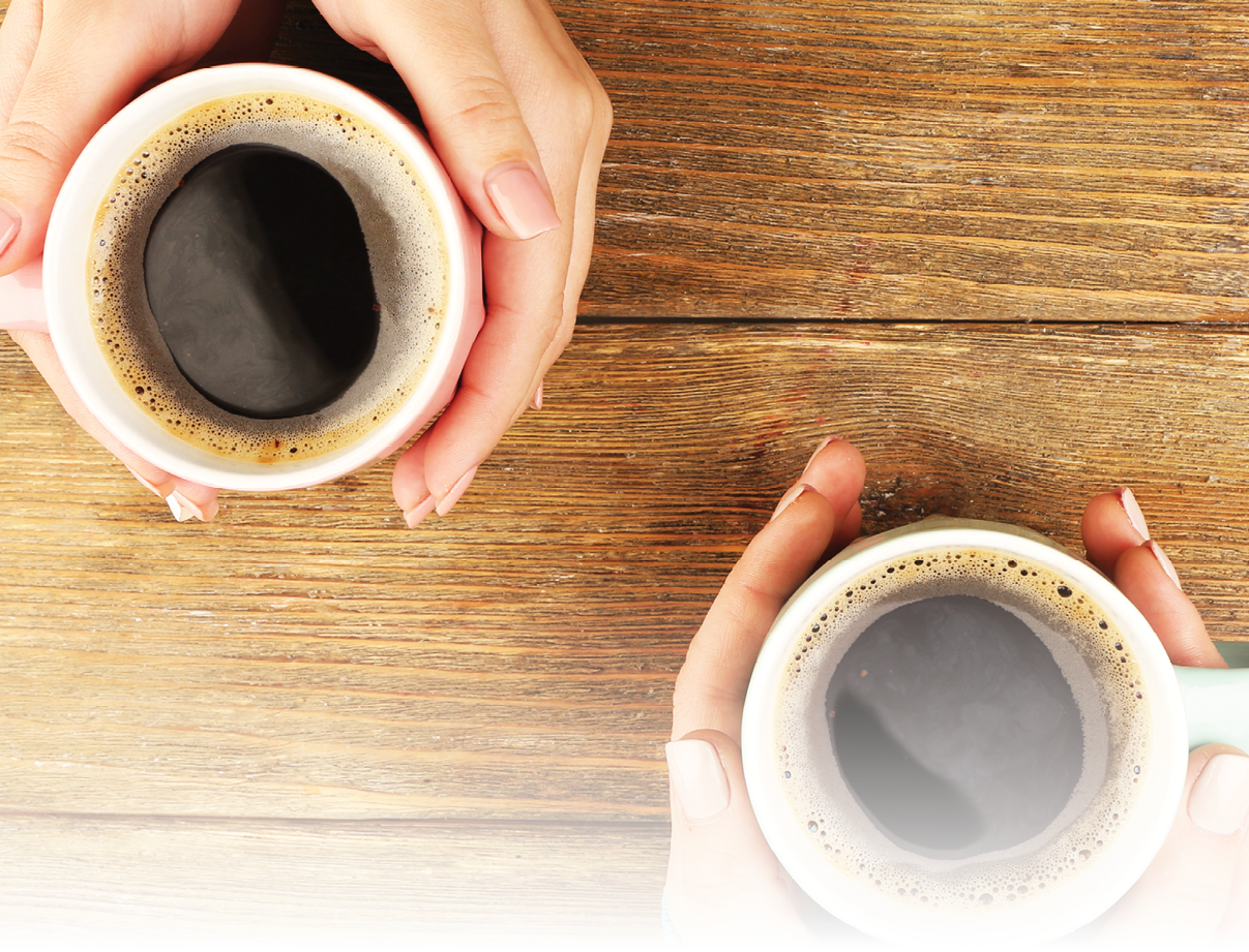 Female hands holding cups of coffee on rustic wooden table background