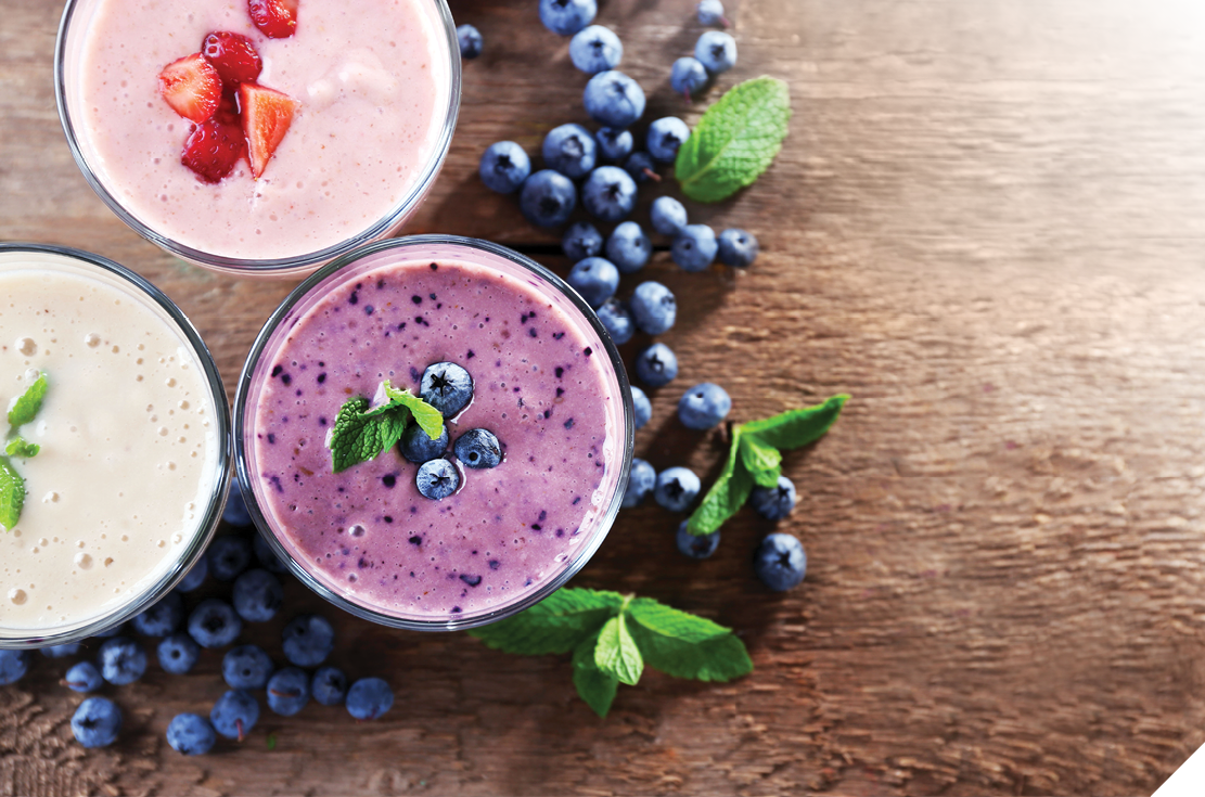 Tasty blueberry, strawberry and milk yogurts with berries and mint around on wooden background
