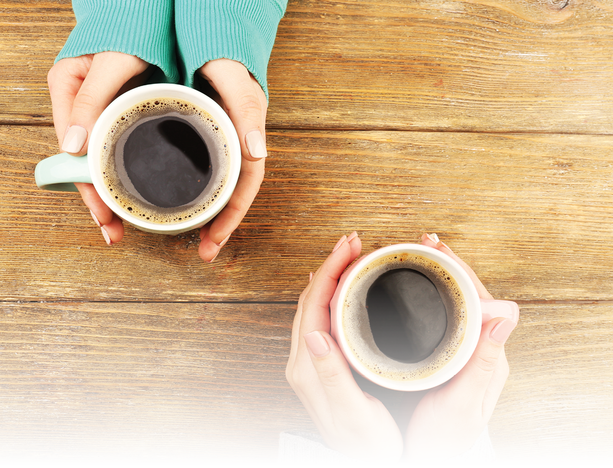 Female hands holding cups of coffee on rustic wooden table background
