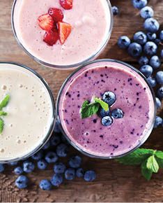 Tasty blueberry, strawberry and milk yogurts with berries and mint around on wooden background