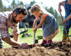 Mature father with small children working outdoors in garden, sustainable lifestyle concept.