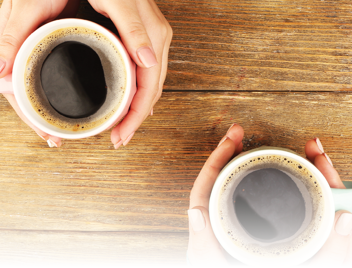 Female hands holding cups of coffee on rustic wooden table background
