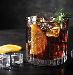 Fresh made Cuba Libre cocktail with brown rum, cola and lemon on wooden background