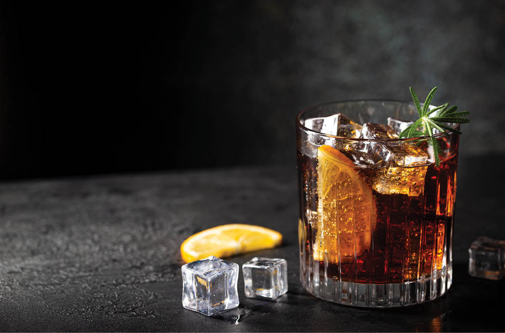 Fresh made Cuba Libre cocktail with brown rum, cola and lemon on wooden background