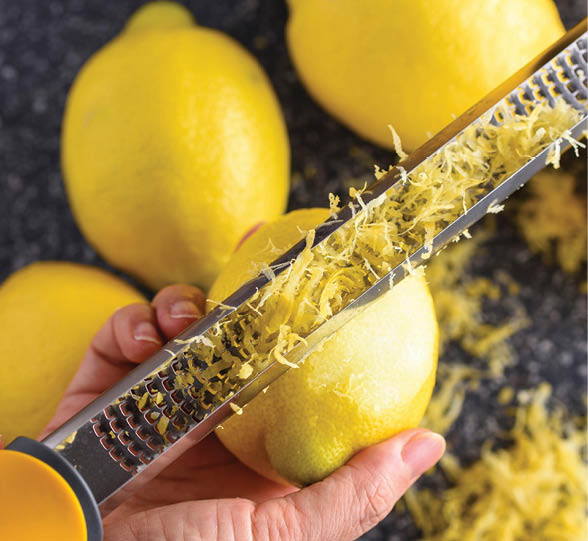 Zesty Citrus: Top-View Close-up of Hand Zesting Lemon for a Burst of Flavor