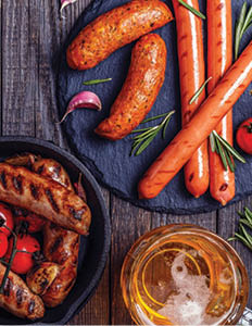 Grilled sausages with glass of beer on wooden table. Top view with copy space.