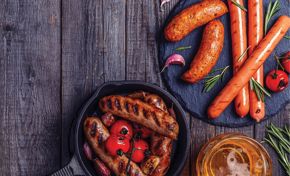 Grilled sausages with glass of beer on wooden table. Top view with copy space.