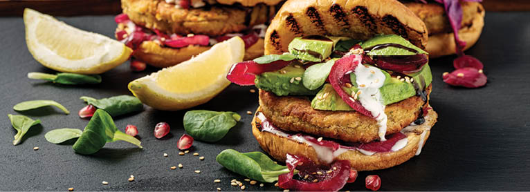 Gourmet vegetarian falafel burger with avocado. The falafel burger is made from; chick peas, white onion, garlic, parsley, dill and coriander. The ingredients are blended together and cooled in the fridge for an hour before being shaped into burgers. They are lightly fried in vegetable oil 2-3 minutes per side. The burger is placed in a toasted brioche bun with some sweet red onion jam, slices of avocado have been places on top and finished off with a glaze of balsamic vinegar and some toasted sesame seeds. Colour, horizontal format with some copy space.