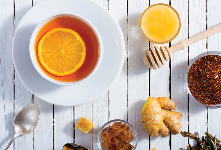 cup of tea, different leaves, honey, lemon ginger and brown sugar on white wooden table background