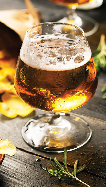 Glass of beer on the black table with potato chips