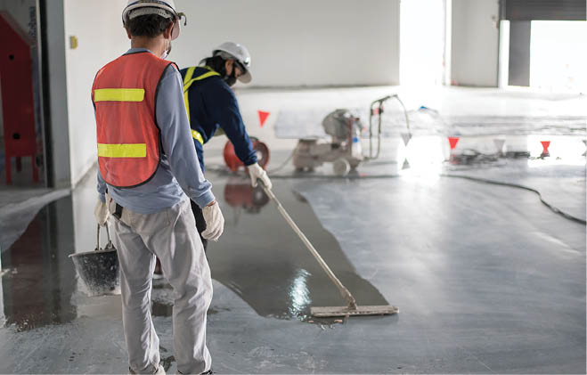 Construction worker painting epoxy flooring or floor hardener