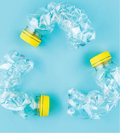Three crashed plastic bottles on blue background form resycling sign. Plastic utilisation concept. Attractive ecological problem positive poster. 