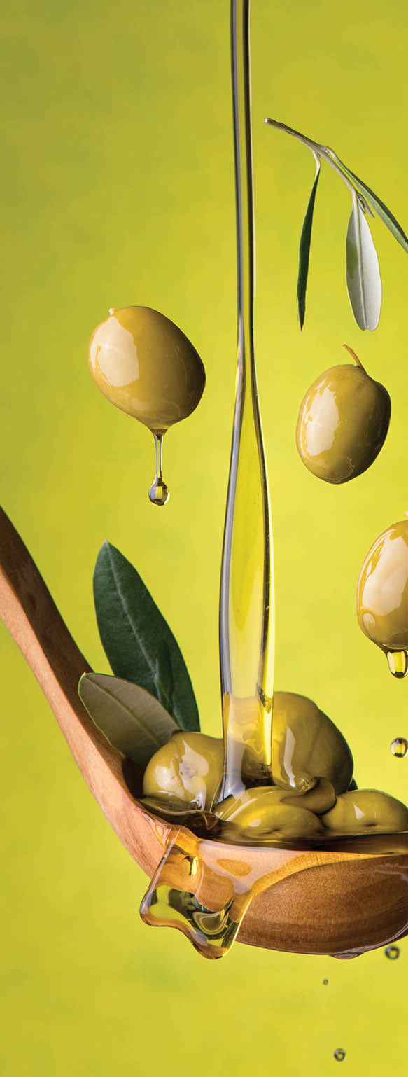 ladle with olives and oil on a green background. Olives, extra virgin olive oil and olive leaves float in the air