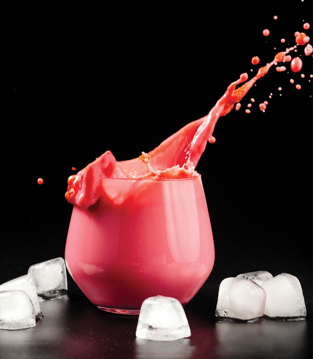A cup of beet latte on a dark background with ice. Healthy eating alternative to caffeine. Beet latte with a splash of