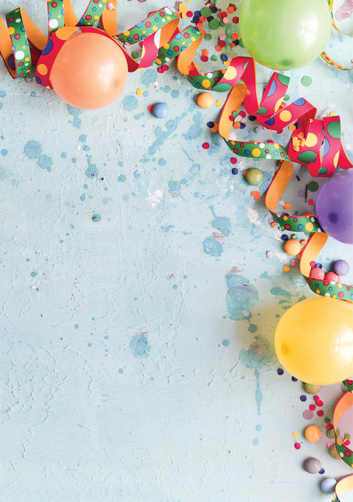 Carnival, festival or birthday balloon background with colorful party streamers, candy and confetti making a border on a blue background with copy space